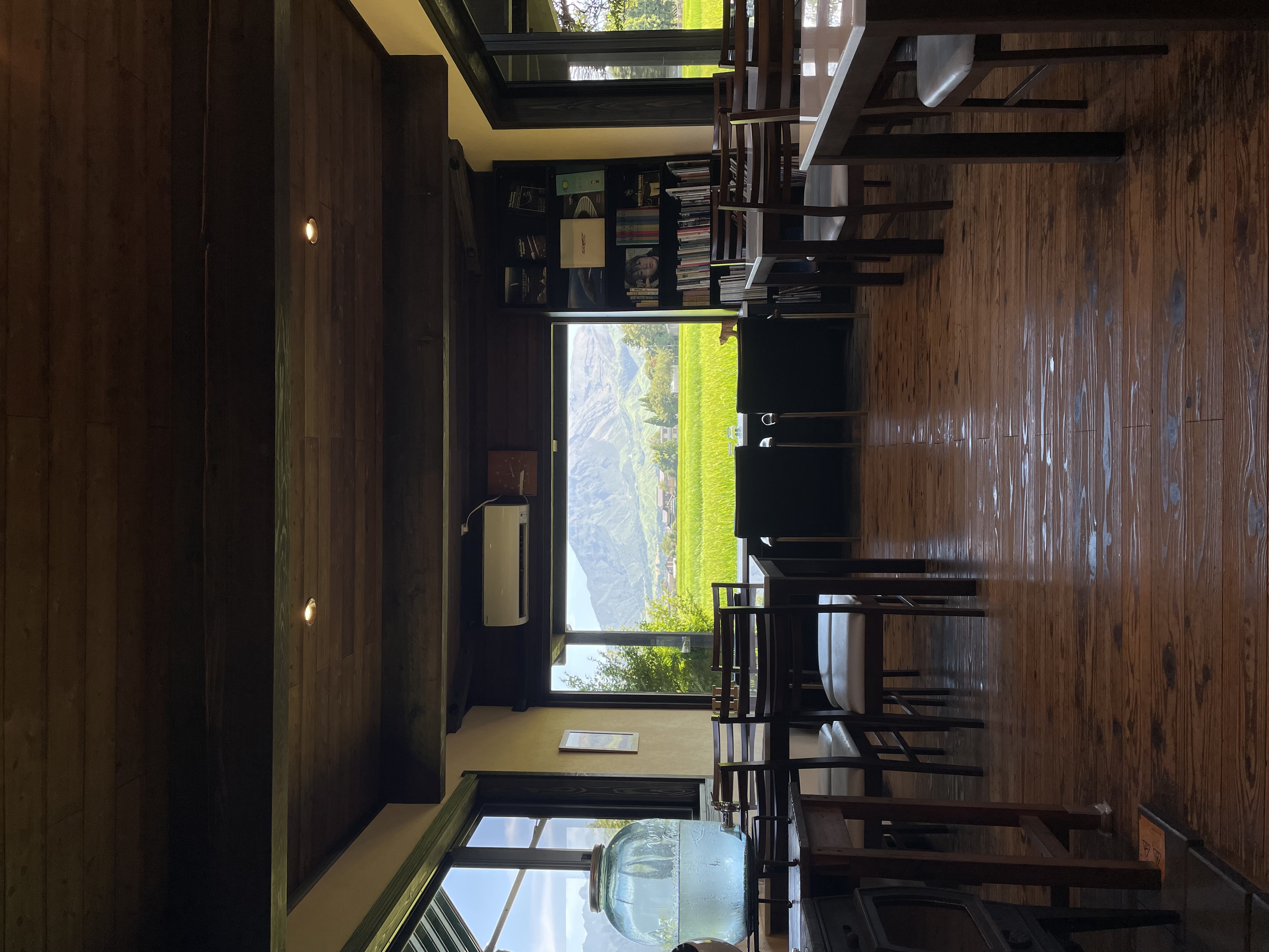店内の窓辺から、田園と阿蘇の山。カウンターと椅子、時計、青いガラスジャー。